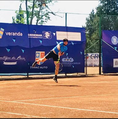 Tennisspieler schlägt den Ball auf einem Sandplatz mit Werbebannern im Hintergrund.